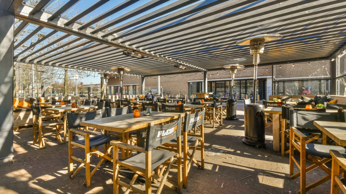 Terraza de restaurante con mesas bajo toldo