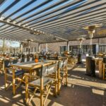 Terraza de restaurante con mesas bajo toldo